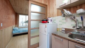 Une cuisine compacte équipée d’un réfrigérateur, d’un évier et d’une fenêtre donnant sur un espace nuit.
