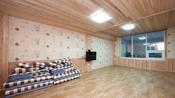Una habitación espaciosa con paneles de madera, un ventanal grande y un televisor fijado a la pared.