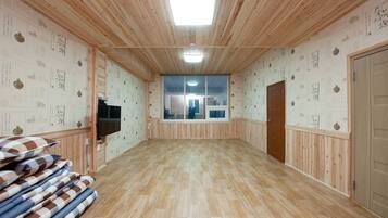 Una habitación con paneles de madera, un televisor, un ventanal grande y una puerta.
