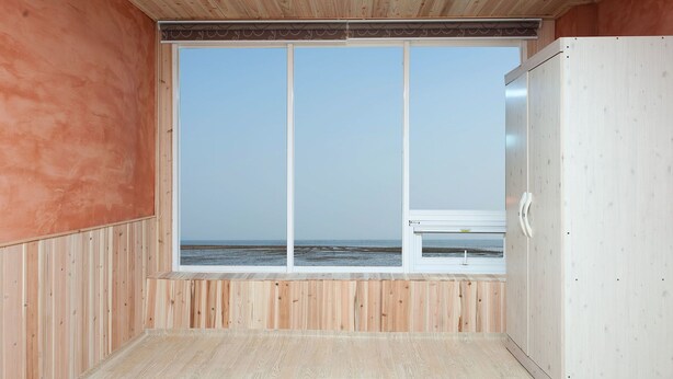 Une chambre dotée d’une grande fenêtre donnant sur la plage.