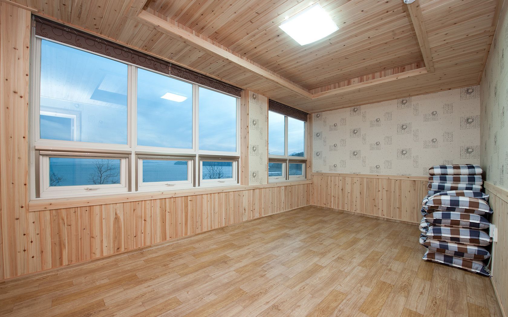 Una habitación con amplios ventanales, paredes de madera y un suelo con patrón de espiga.