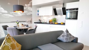 A modern kitchen with white cabinets, a built-in oven, and a dining area with a table set for two.