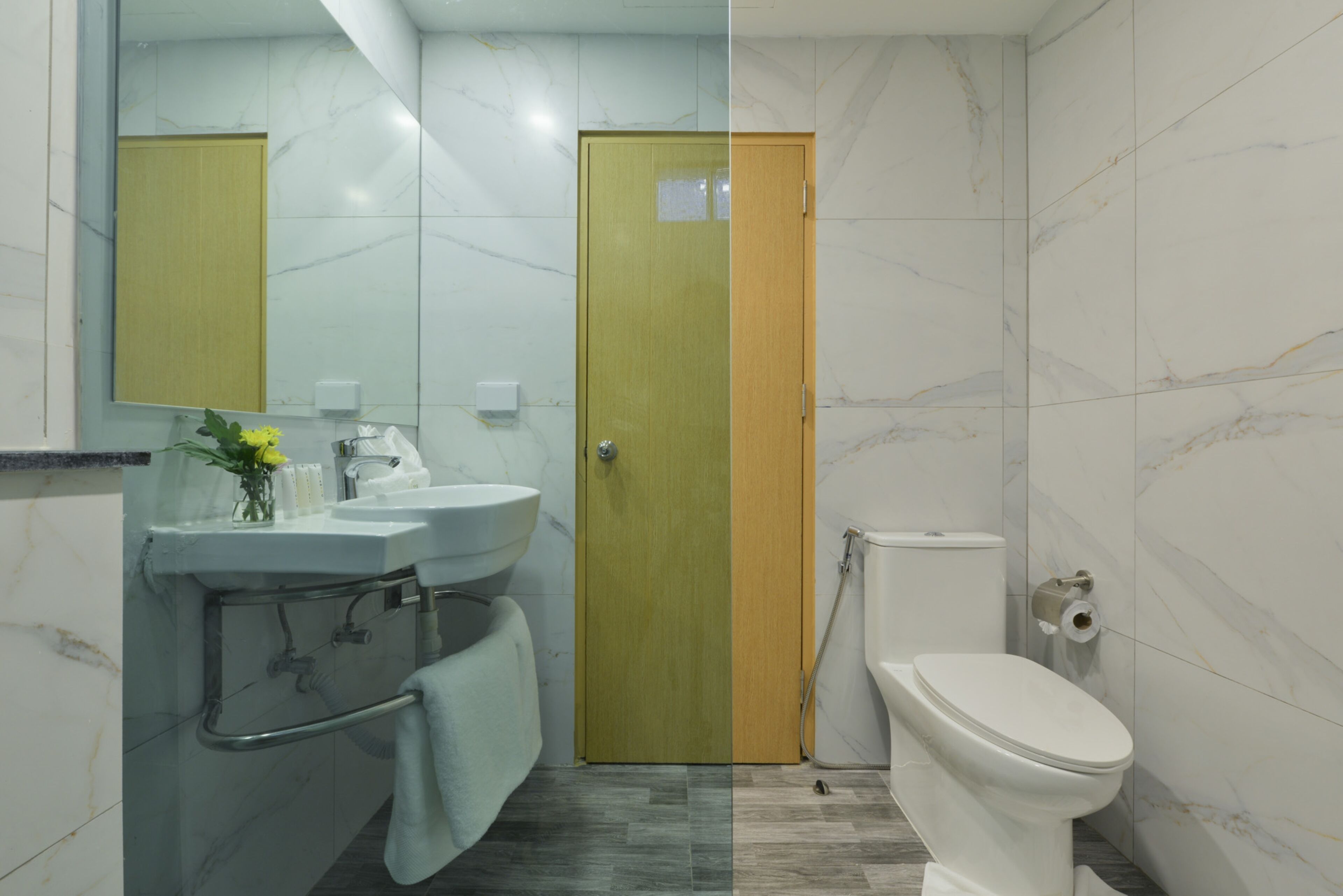 Een badkamer met een wastafel, spiegel, toilet en een deur.
