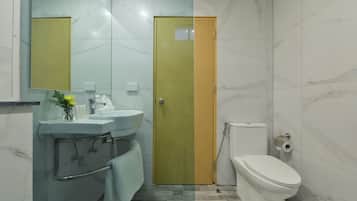 Een badkamer met een wastafel, spiegel, toilet en een deur.