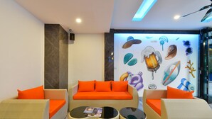 Una sala de estar moderna con un sofá, dos mesas redondas y un mural en la pared.