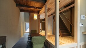 A modern interior with a wooden staircase, a dining area with a table and chairs, and a view of the outdoors.