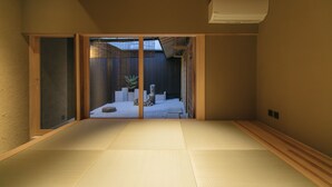 A traditional Japanese room with tatami flooring, sliding doors, and a view of a garden.