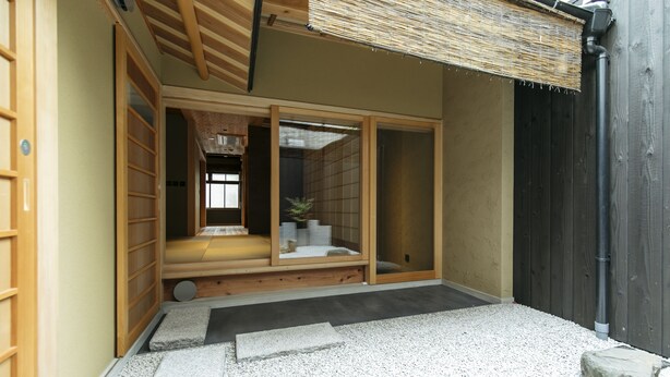 A traditional Japanese room with tatami flooring, sliding doors, and a small garden area with stepping stones.