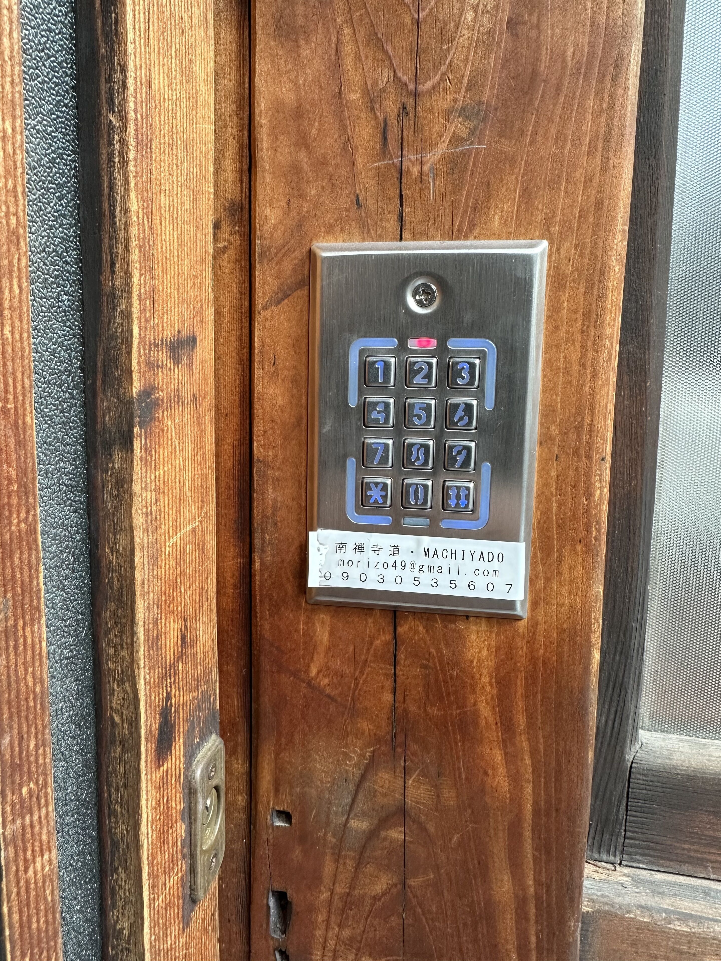 A wooden door with a metal keypad lock.