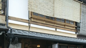 A traditional Japanese building with a wooden entrance, a signboard, and a fire extinguisher outside.
