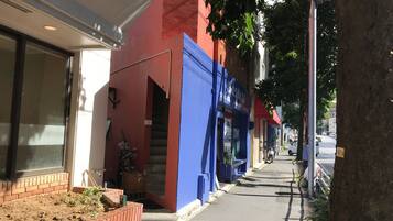 A narrow street with a row of buildings, one with a blue facade and a red door.