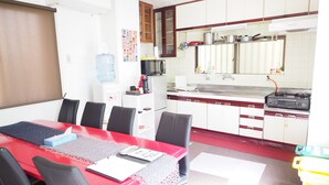 A dining area with a red table, black chairs, and a water dispenser. - Holiday Homes TSUBOYA 2nd (Naha)
