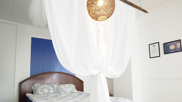 A bedroom with two beds, a wooden headboard, and a white canopy. - Holiday Homes TSUBOYA 2nd (Naha)
