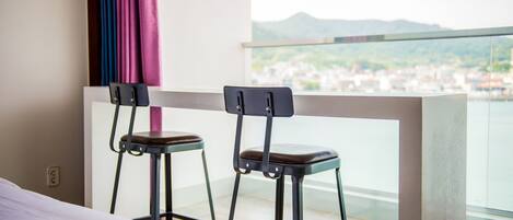 Un balcone con due sgabelli e un letto.