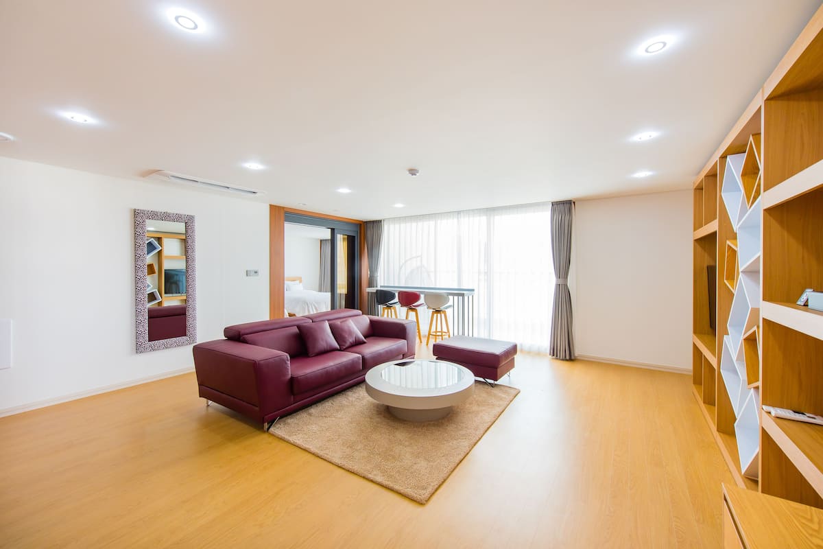 A modern living room with a red sofa, a glass coffee table, and wooden shelves.