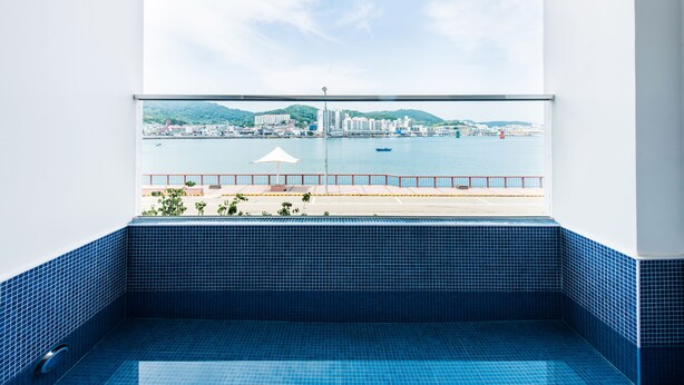 Un balcón con suelo de baldosas azules y vistas a un puerto deportivo con barcos y edificios.