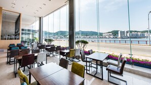Un restaurante moderno con amplios ventanales que ofrece vistas a un paisaje urbano y una masa de agua.