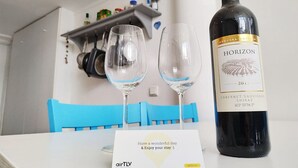 A bottle of Horizon 2017 Cabernet Sauvignon Shiraz on a table with two empty wine glasses and a card that says "Have a wonderful day & Enjoy your stay". - AirTLV Centrally Located Studio With Gallery (Tel Aviv)