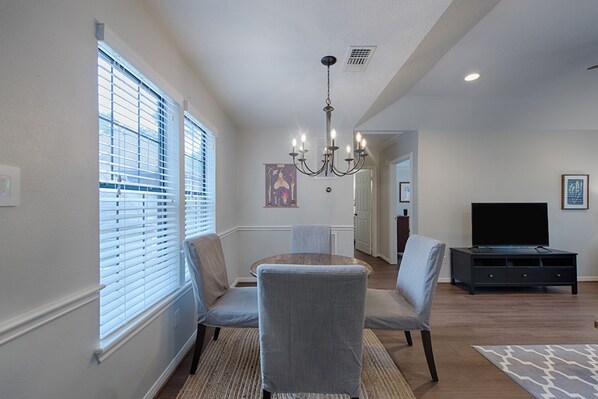 A dining area with a chandelier, a television, and a rug.