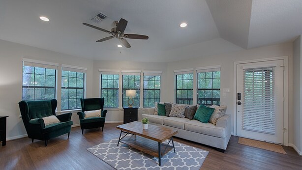 A spacious living room with a ceiling fan, large windows, a sofa, two armchairs, and a coffee table. - Spacious 1BR Apt Retreat in The Woodlands: Private, Peaceful, Great Location (Spring)