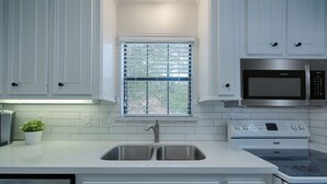 A kitchen with white cabinetry, a stainless steel sink, a microwave, and an oven. - Spacious 1BR Apt Retreat in The Woodlands: Private, Peaceful, Great Location (Spring)