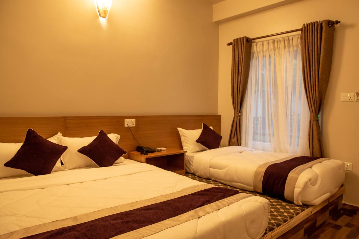 Two single beds with headboards, a bedside table with a phone, and a window with curtains.