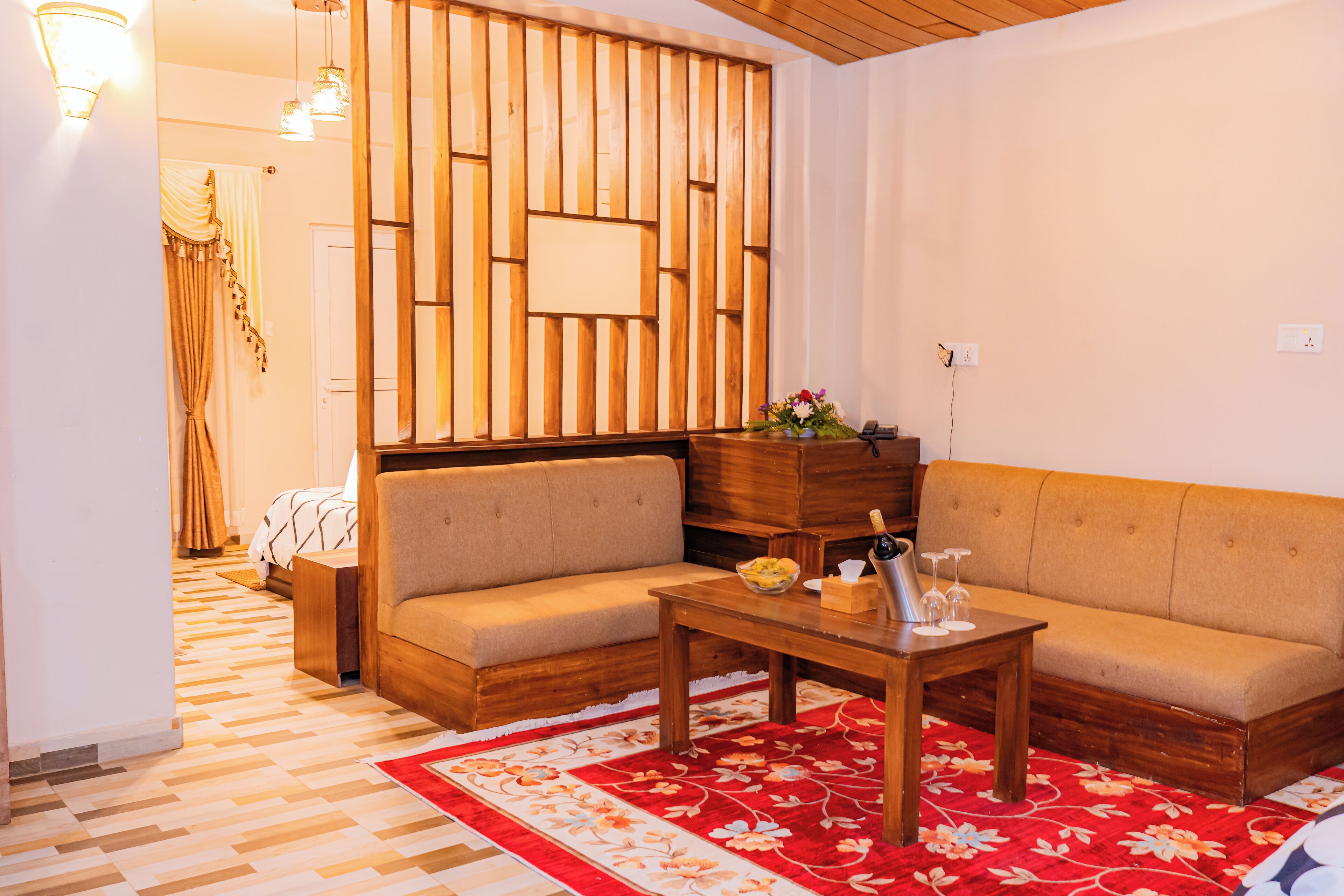 A cozy living room with two sofas, a wooden coffee table, and a red floral rug.