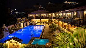 Un hotel con piscina, zona de estar al aire libre y entrada bien iluminada.