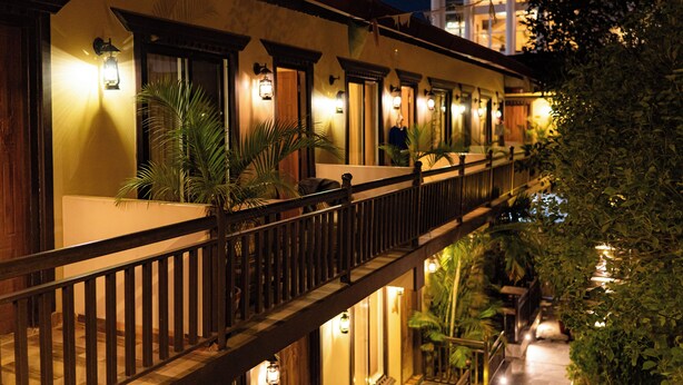 Un hotel con balcón, plantas en macetas e iluminación cálida.