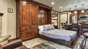 Une chambre à coucher avec une grande armoire en bois, un lit avec une literie à motifs, un canapé en cuir et une cheminée en pierre.