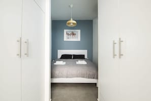 A bedroom with a bed, white wardrobe, and a hanging light fixture.