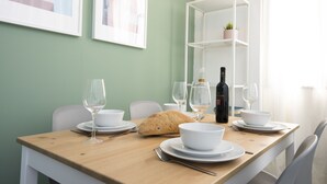 A dining table set with white plates, bowls, and wine glasses, a loaf of bread, and a bottle of wine. - AirTLV Comfortable 3 BDRM in Old North (Tel Aviv)