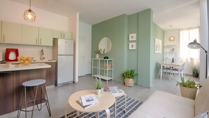 A modern kitchen with a dining area, a living room with a sofa, and a dining table. - AirTLV Comfortable 3 BDRM in Old North (Tel Aviv)