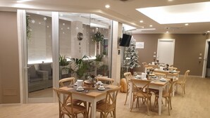 A dining area with multiple tables and chairs, a Christmas tree, and a television mounted on the wall. - B&B L'Abbazia (Torremaggiore)