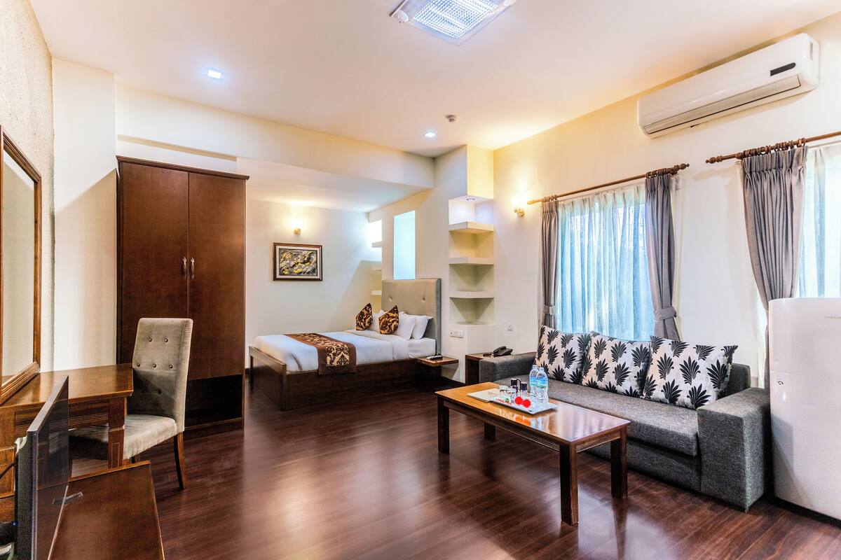 Una habitación de hotel con cama, sofá, sillón y escritorio.