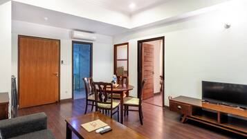 Una sala de estar moderna con una mesa de centro de madera, un sofá gris, un mueble para televisión y un comedor con sillas y una mesa.