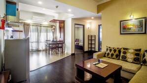A modern living room with a sofa, coffee table, and a dining area with chairs and a table. - Suite Homes, Serviced Apartment Hotel (Lalitpur)