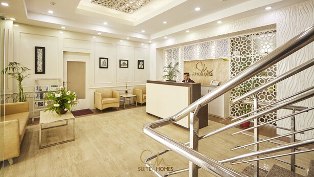 A hotel reception area with a reception desk, seating area, and a staircase. - Suite Homes, Serviced Apartment Hotel (Lalitpur)