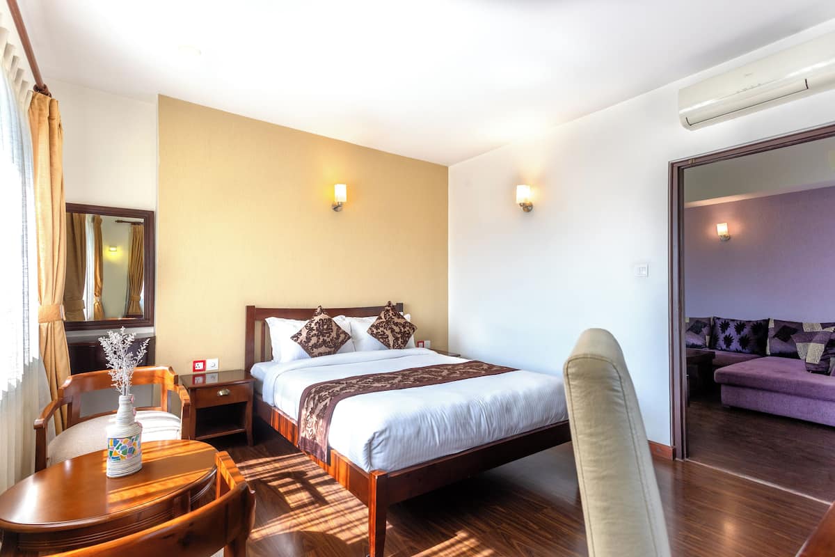 Una habitación de hotel con cama, mesita de noche, silla y sofá.