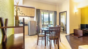 A modern living room with a dining area, a kitchen, and a balcony with a view. - Suite Homes, Serviced Apartment Hotel (Lalitpur)