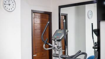 An exercise machine with a digital display, a wooden door, and a wall clock.