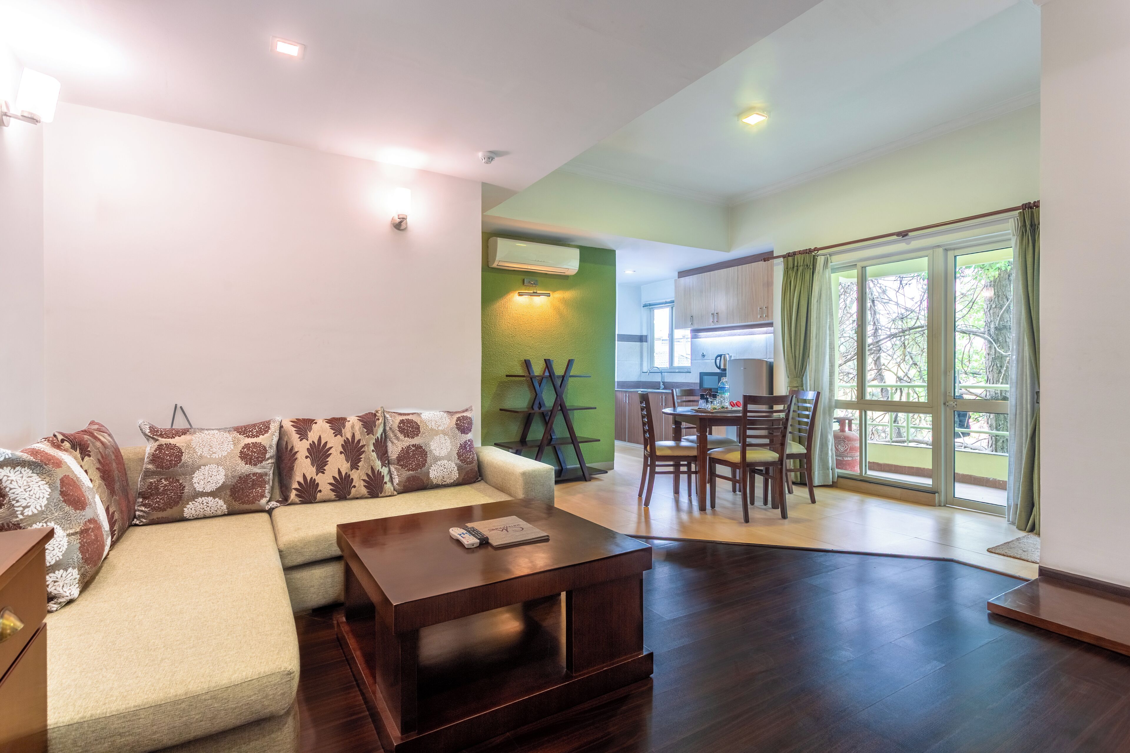 A modern living room with a sofa, coffee table, and a dining area with chairs and a table.