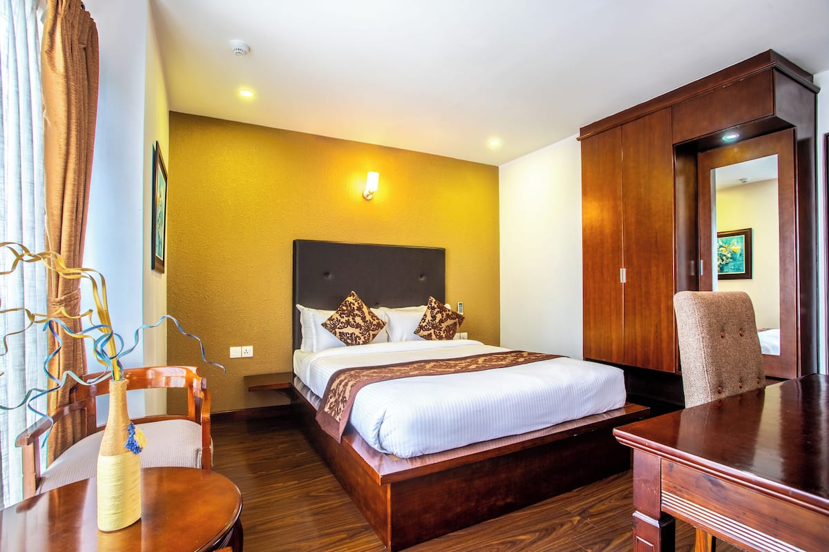 Una habitación de hotel con una cama, muebles de madera y un escritorio.
