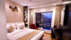 A modern hotel room with a large bed, a small table, a red chair, and a view of the outside. - Hotel City Pride (New Delhi)