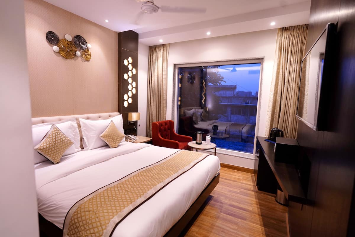 Une chambre d’hôtel moderne avec un grand lit, une petite table, une chaise rouge et une vue sur l’extérieur.