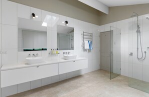 A modern bathroom with two sinks, a large mirror, and a glass-enclosed shower area. - Oceans Edge Beach House At Oak Beach (Oak Beach)