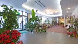 A spacious indoor area with multiple potted plants, a reception desk, and a staircase leading to another level. - Hotel Hananoki (Nikko)