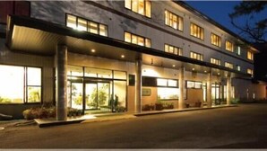 A hotel with a covered entrance, large windows, and outdoor plants. - Hotel Hananoki (Nikko)