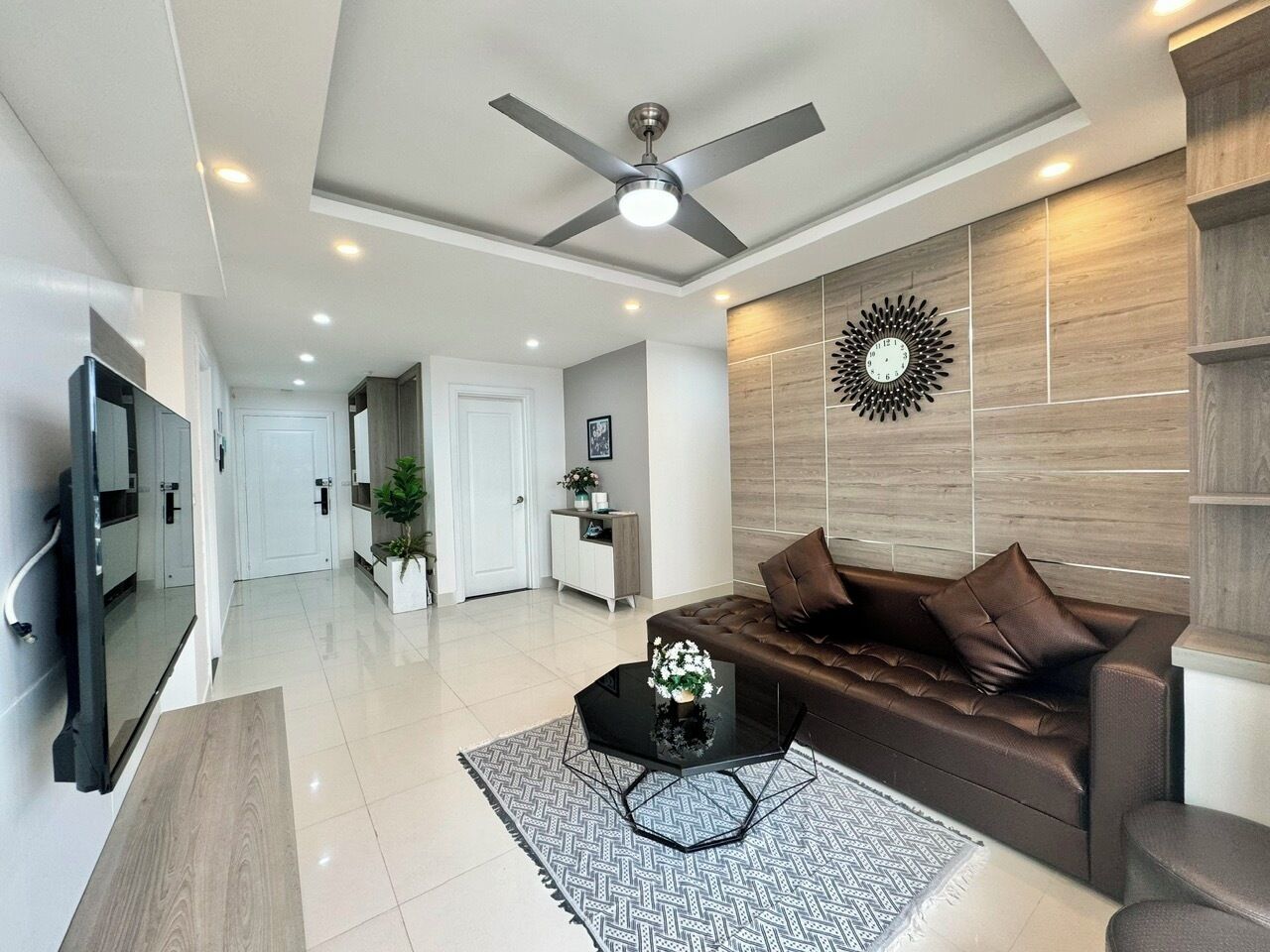 A modern living room with a brown leather sofa, a black coffee table, and a ceiling fan.