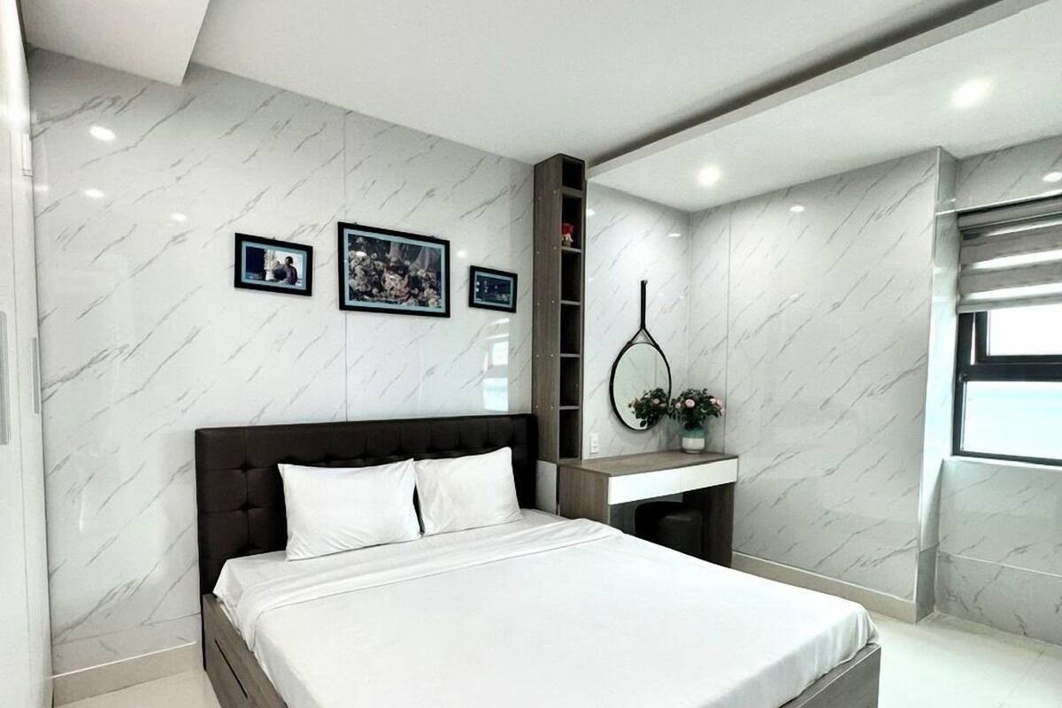 A modern bedroom with a large bed, marble walls, and a built-in shelf.